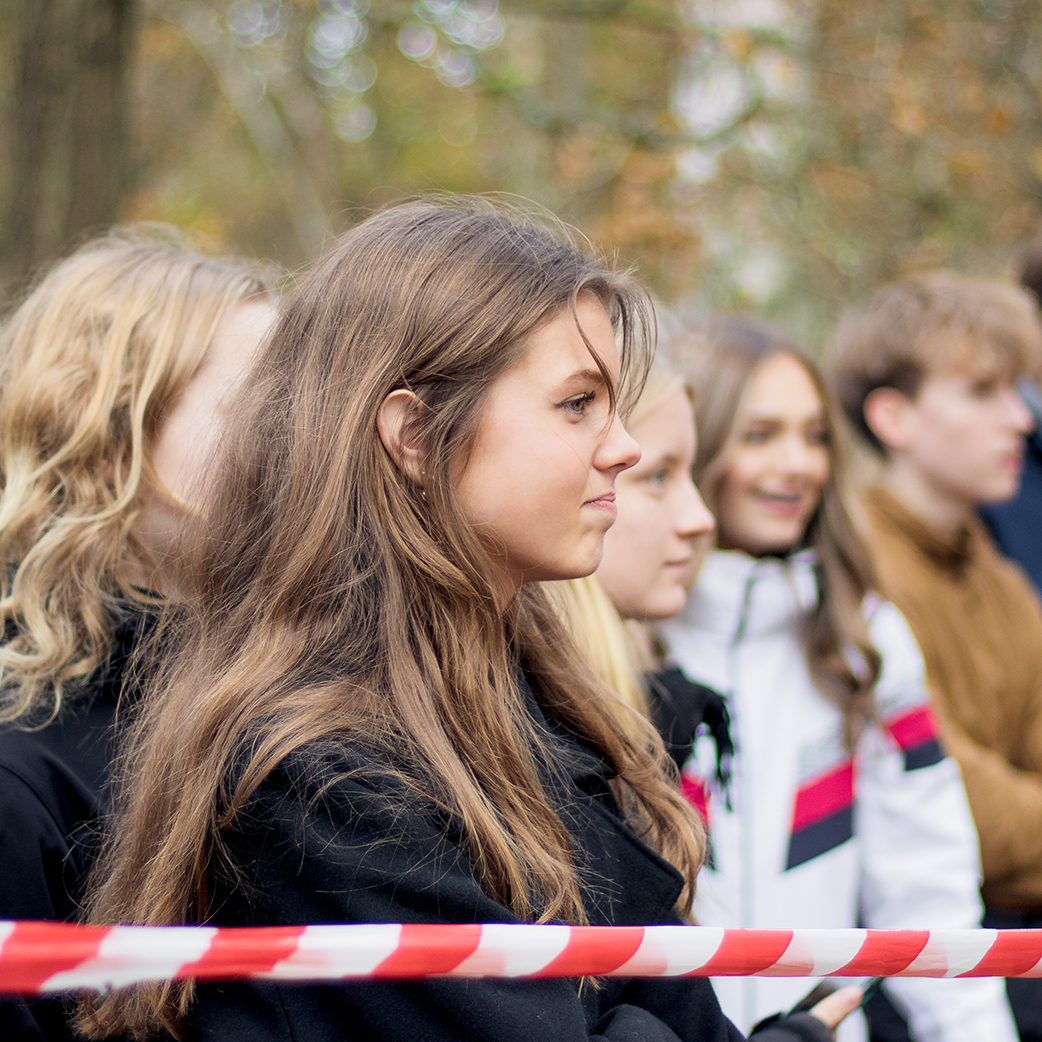 En gruppe elever fra Slotshaven Gymnasium står udenfor og kigger i samme retning. Kameraret har fokuseret på en ung pige.