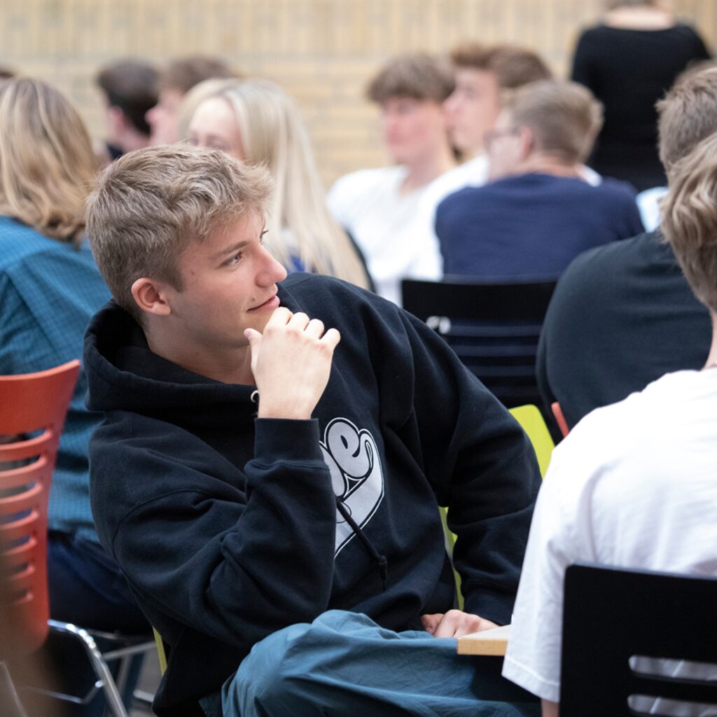 En tidligere elev fra Slotshaven Gymnasium sidder på en stol i skolens kantine.