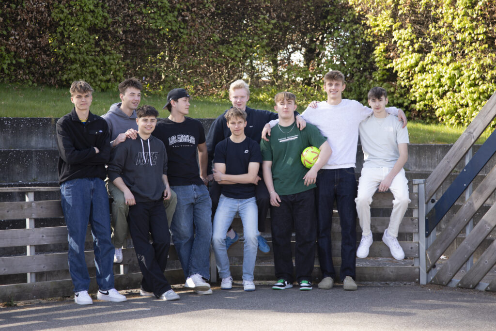 En gruppe drenge på ni står og poserer for kameraet, med en fodbold.