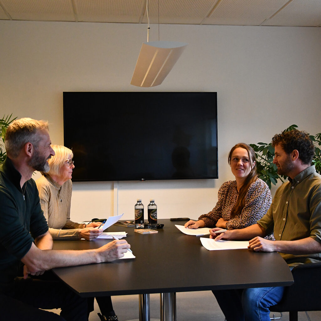 Fire voksne holder møde ved et bord. De har alle papirer foran sig. En af de til tilstedeværende er Slotshaven Gymnasiums rektor.